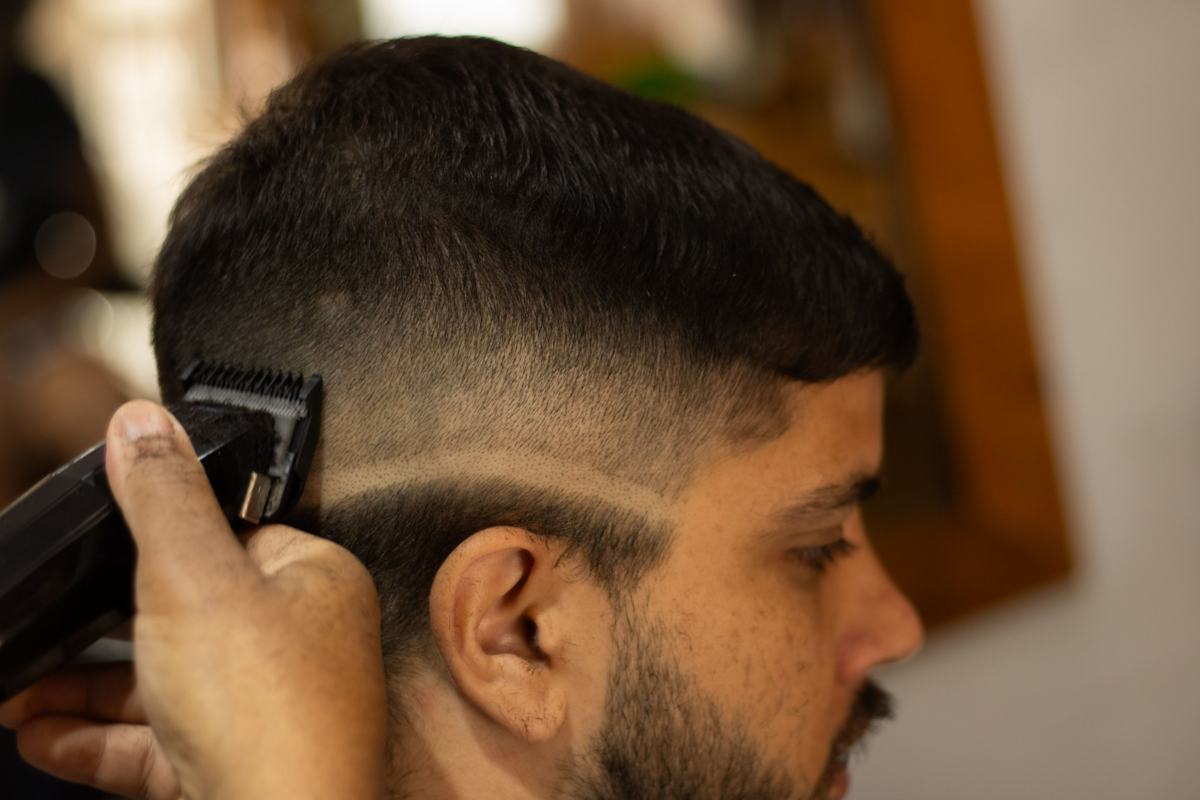 Illustrative image: barber trimming a fade haircut