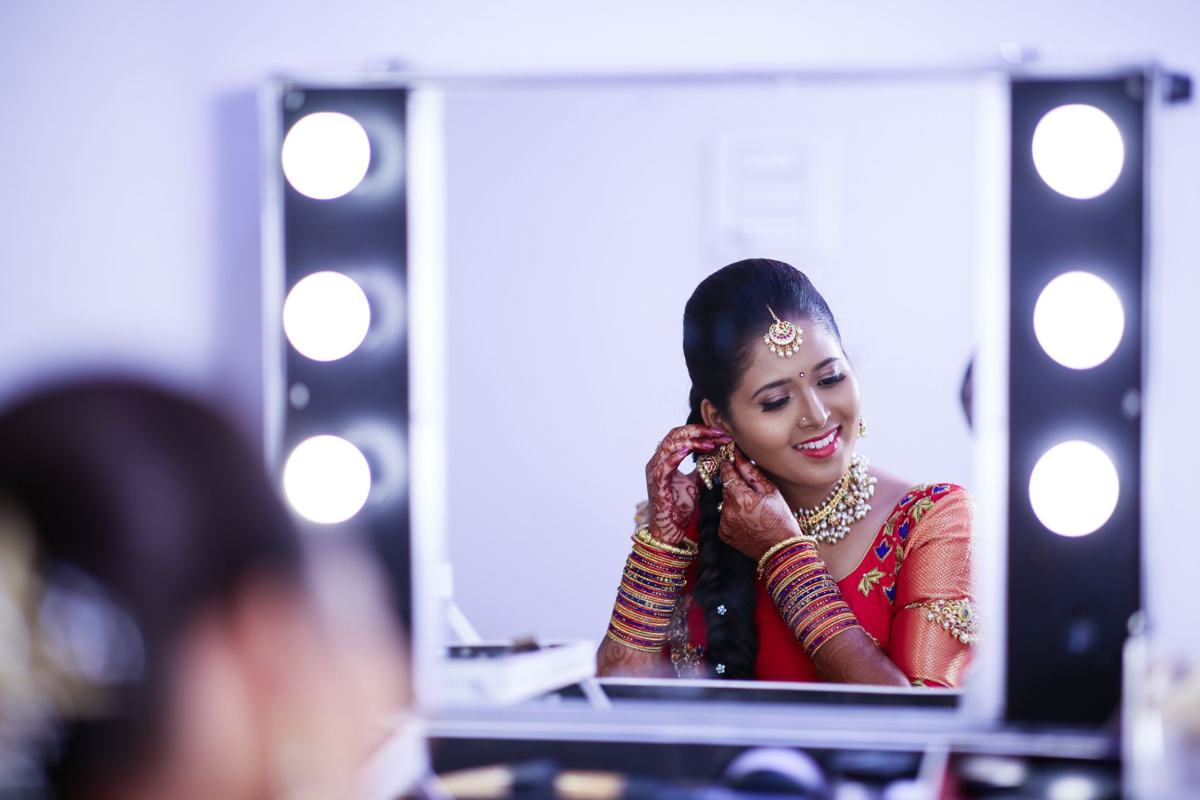 Illustrative image: woman getting ready at a lit makeup mirror