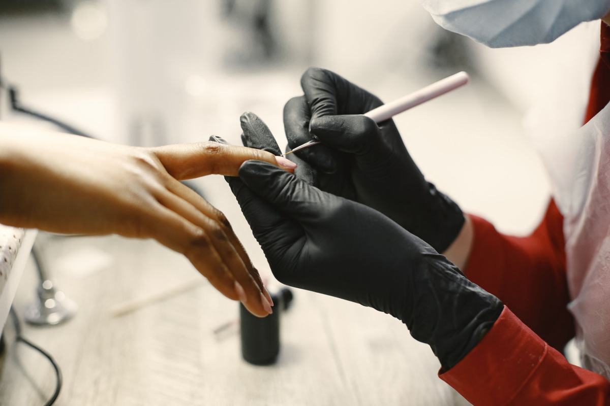 Illustrative image: nail technician painting a fine nail design