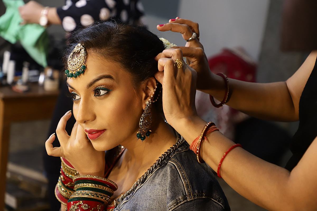 Illustrative image: stylist setting hair and a maang tikka